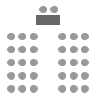 Chairs in rows facing front of room with one table at front and two chairs facing back